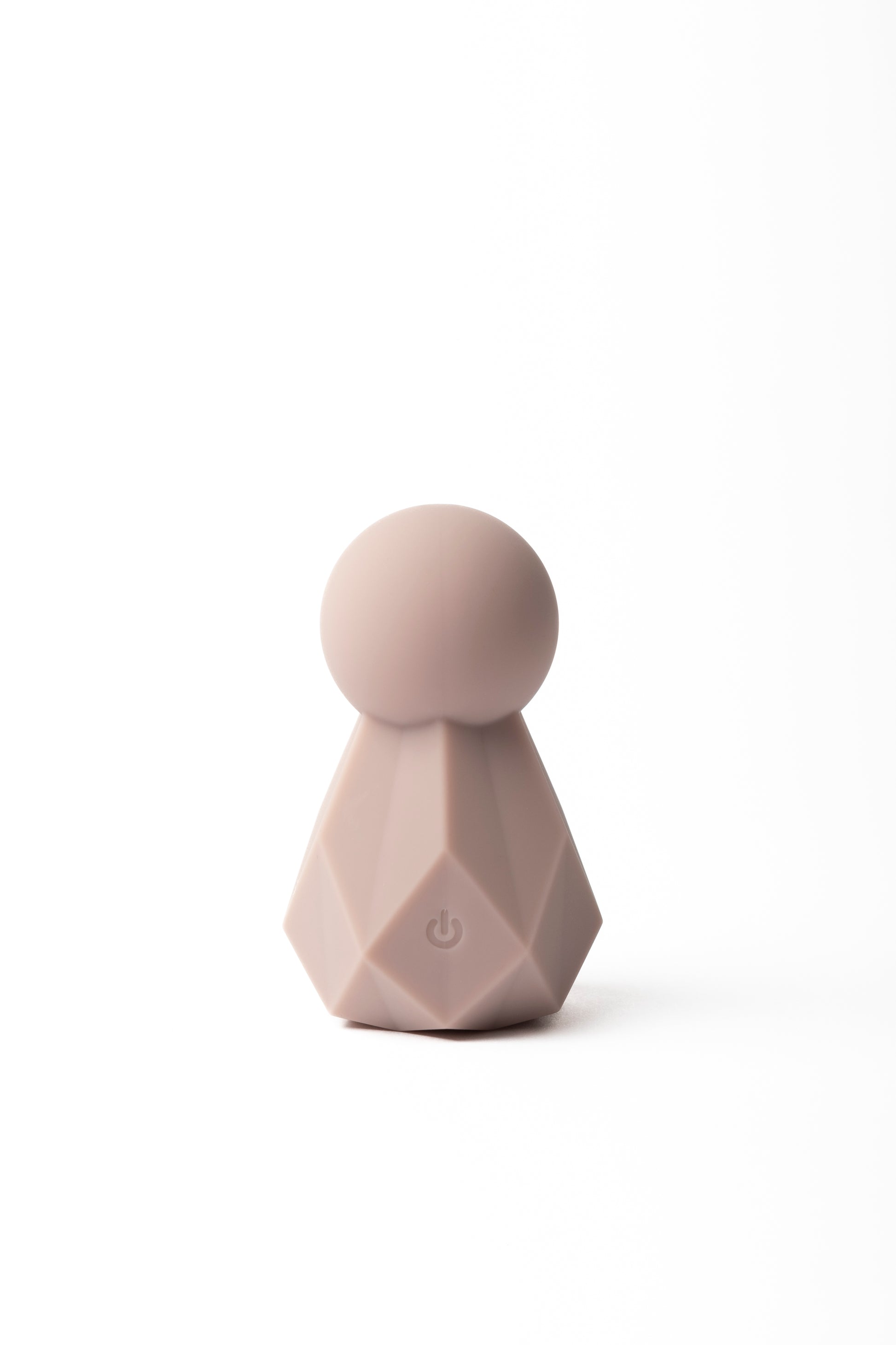 Compact silicone wellness massager with a soft rounded top and faceted base, shown in a blush tone. Presented with matching packaging for a clean, modern look.